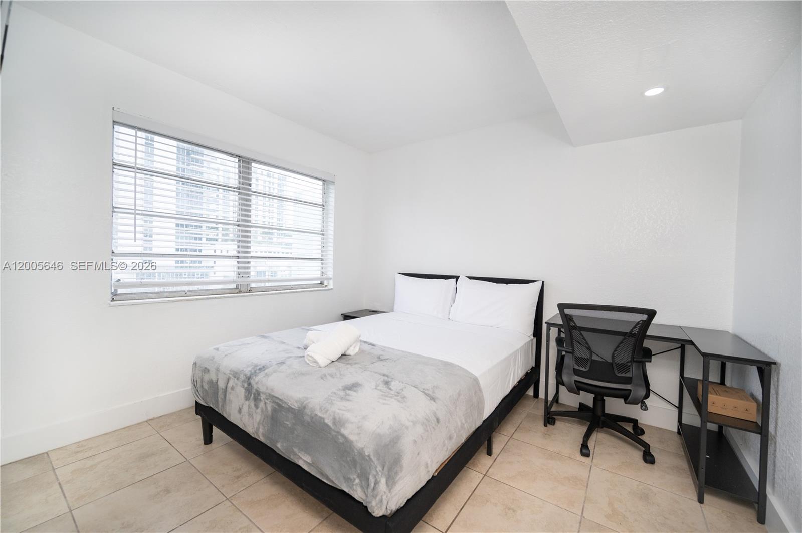 A bedroom features a bed, a desk with a chair, and a window with blinds — 500 NE 26th St # 5D, Miami FL 33137, MIAMI, FL