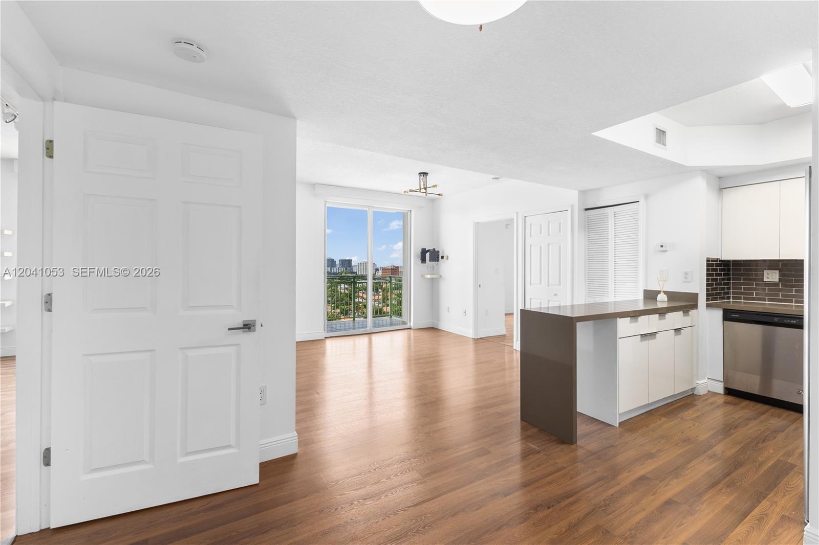 An open-concept living area features wood flooring, a kitchen island, and a balcony with views — 3500 Coral Way # 1509, Miami FL 33145, MIAMI, FL
