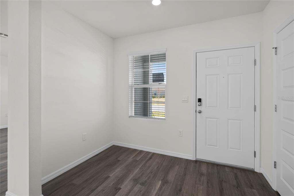 An entryway with white walls, wood-look flooring, a single window, and a white front door — 1734 HUMMINGBIRD ROAD, WINTER HAVEN, FL