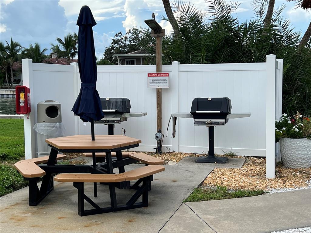 An outdoor grilling area features two gas grills, a picnic table, and a white fence — 4900 BRITTANY DRIVE S UNIT 305, ST PETERSBURG, FL