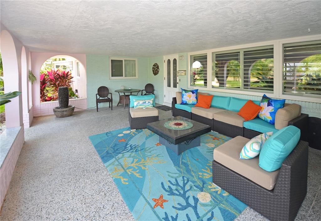 A covered patio features a sectional sofa, a coffee table, and a blue coral-patterned rug — 7020 MANGO AVENUE S, ST PETERSBURG, FL