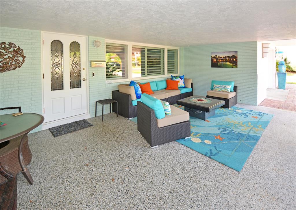 A covered patio features light blue brick walls, wicker furniture, and a blue area rug — 7020 MANGO AVENUE S, ST PETERSBURG, FL
