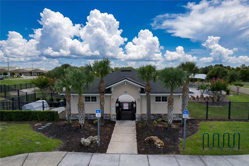 An exterior view of a community pool entrance building with palm trees and handicap parking — 148 LUDISIA LOOP, DAVENPORT, FL