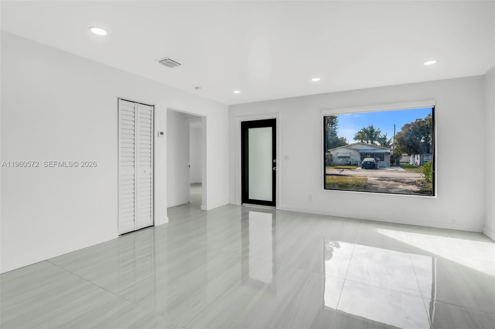 A bright, empty room features white walls, glossy tiled floors, recessed lighting, and a window — 528 NW 3rd Ct, Hallandale Beach FL 33009, HALLANDALE BEACH, FL