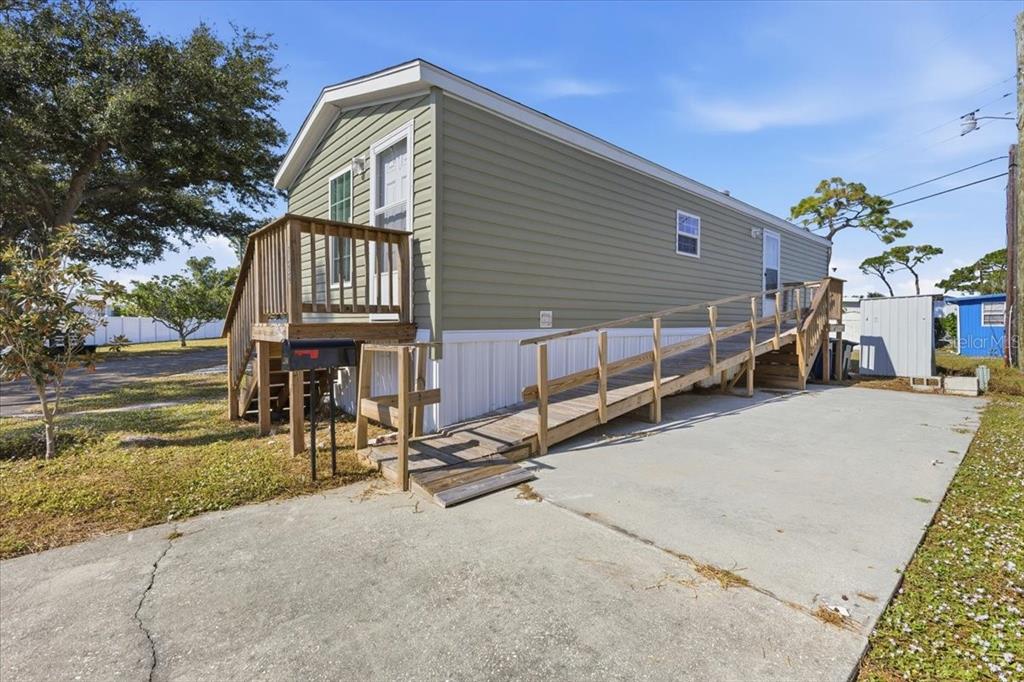 A light green mobile home features a wooden wheelchair ramp and a small front porch — 1800 ENGLEWOOD ROAD UNIT 166, ENGLEWOOD, FL