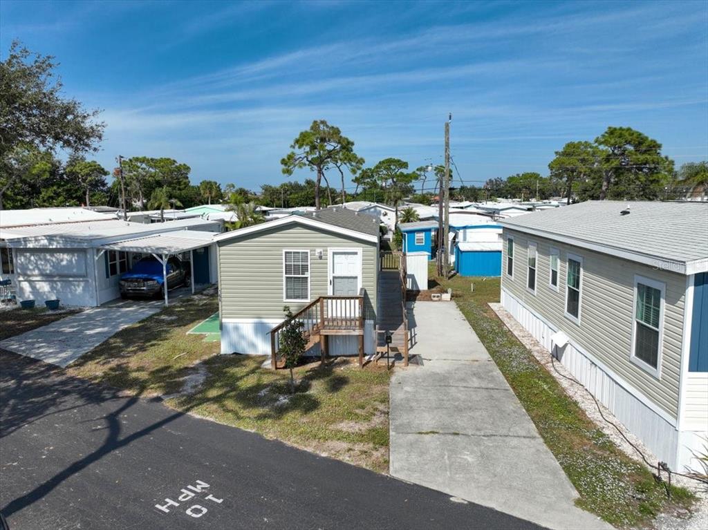 An exterior view of a light green manufactured home with a concrete driveway and ramp — 1800 ENGLEWOOD ROAD UNIT 166, ENGLEWOOD, FL