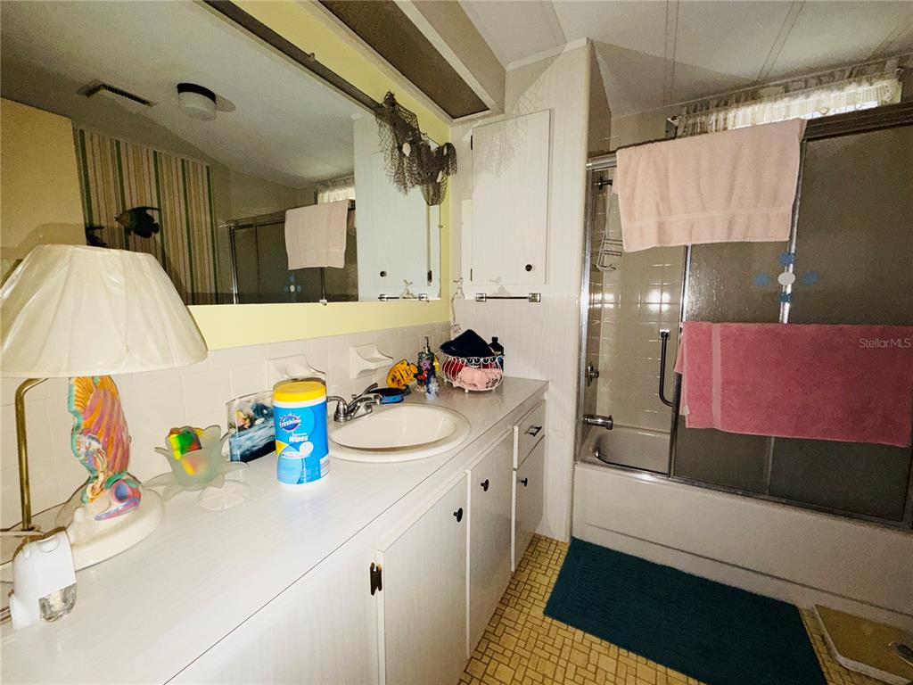 A bathroom features a white vanity with a sink, a mirror, and a shower-tub combination — 2331 BELLEAIR ROAD UNIT 206, CLEARWATER, FL