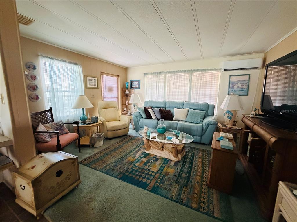 A living room features a blue sofa, patterned area rug, and a wooden chest — 2331 BELLEAIR ROAD UNIT 206, CLEARWATER, FL