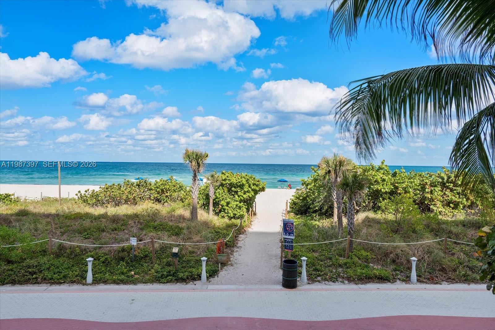 A sandy path leads through dunes to a beach with the ocean in the background — 5555 Collins Ave # 11A, Miami Beach FL 33140, MIAMI BEACH, FL
