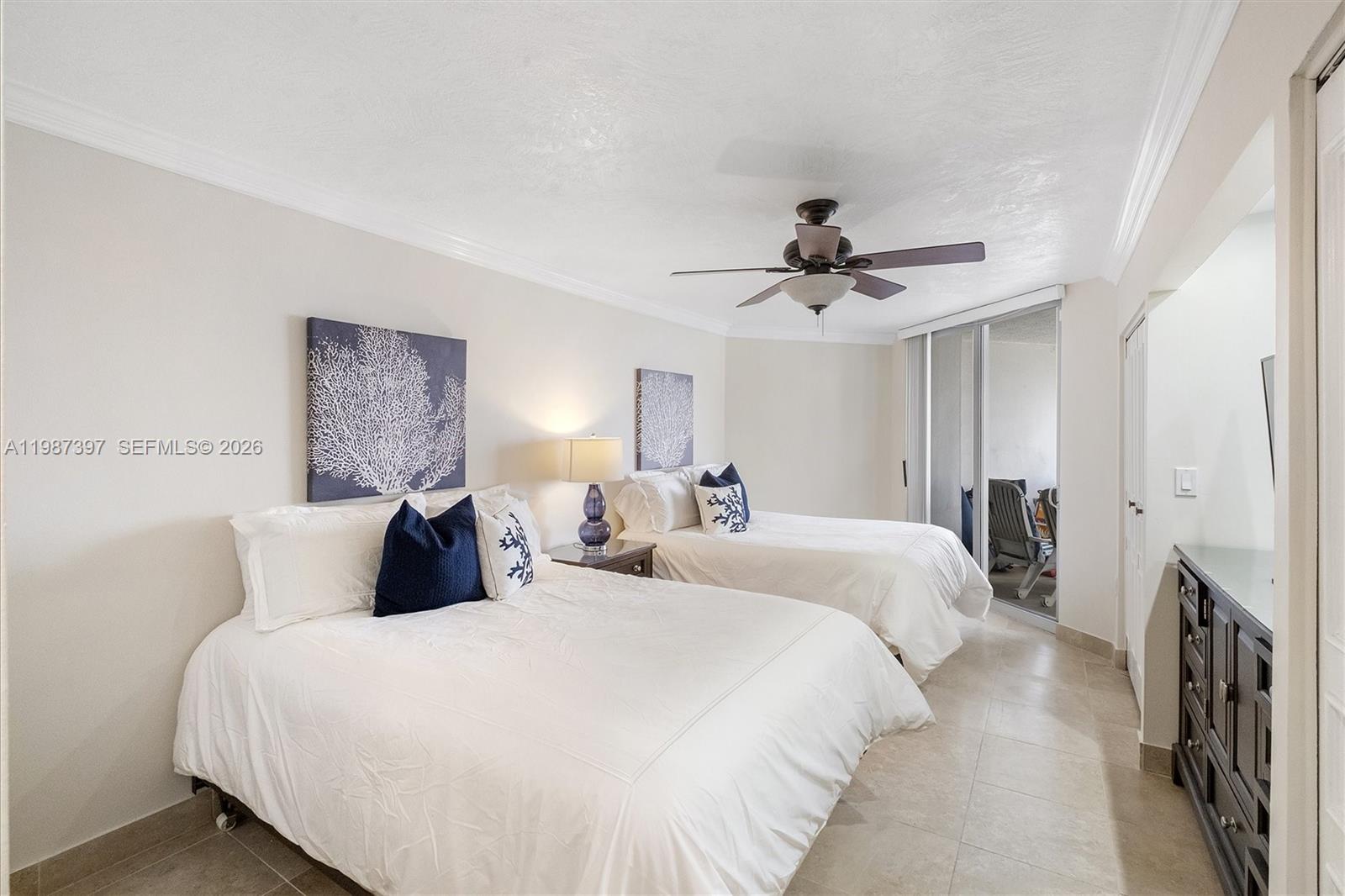 A bedroom features two beds, a ceiling fan, and a sliding glass door to a balcony — 5555 Collins Ave # 11A, Miami Beach FL 33140, MIAMI BEACH, FL