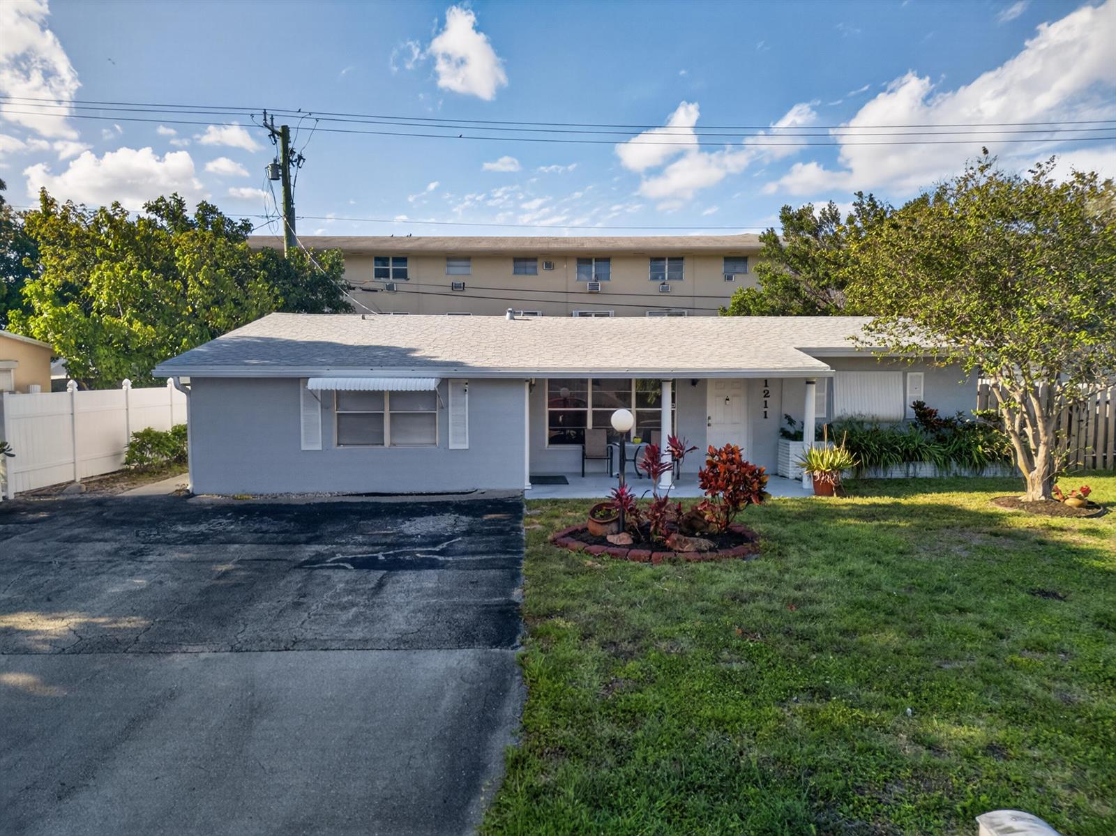 A single-story gray house with a driveway, a front porch, and a small garden bed — 1211 NE 35th Street, Pompano Beach FL 33064, POMPANO BEACH, FL