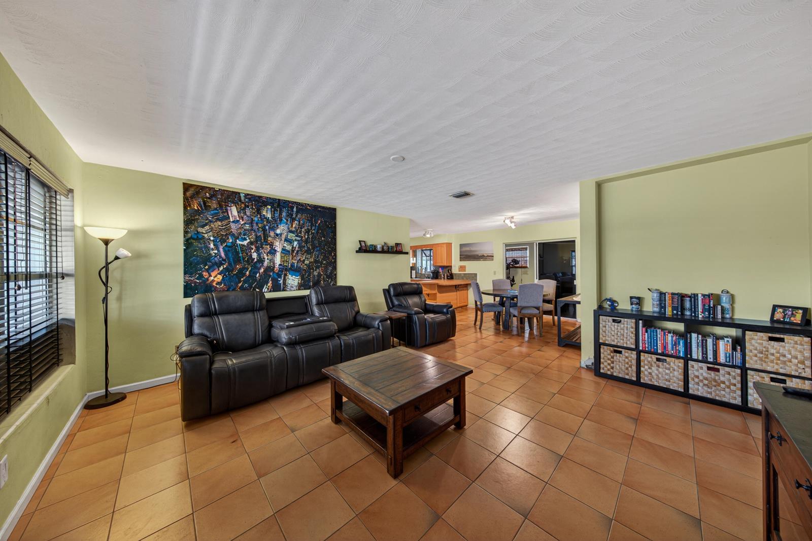 A living room with tile floors, a black leather sofa, and a city skyline wall art — 1211 NE 35th Street, Pompano Beach FL 33064, POMPANO BEACH, FL