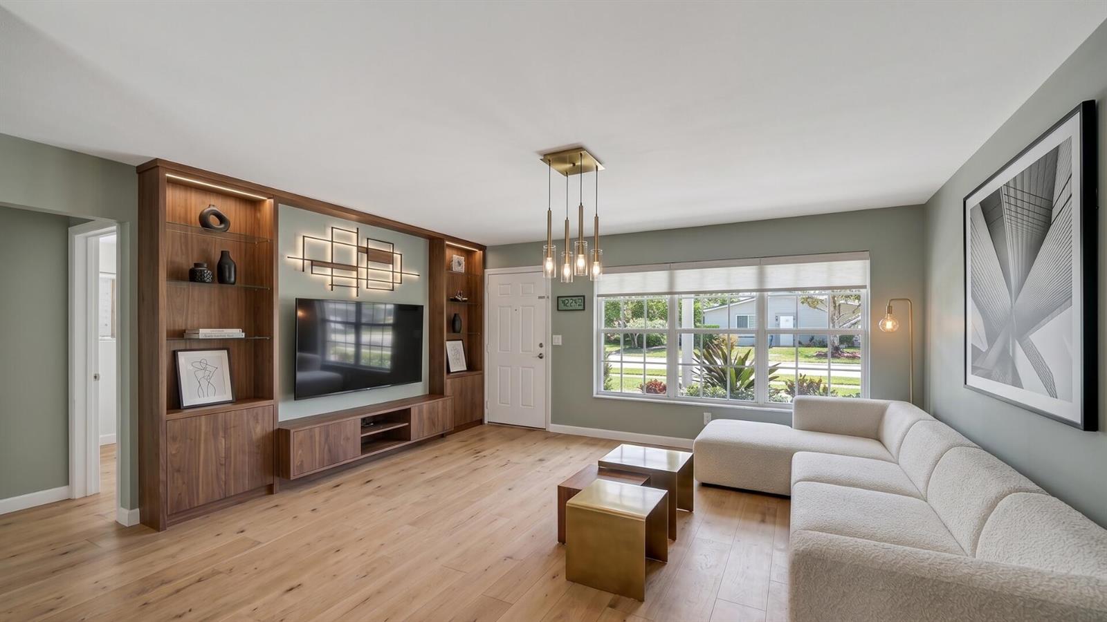 A living room features light wood floors, a built-in media wall, and a white sectional sofa — 1211 NE 35th Street, Pompano Beach FL 33064, POMPANO BEACH, FL