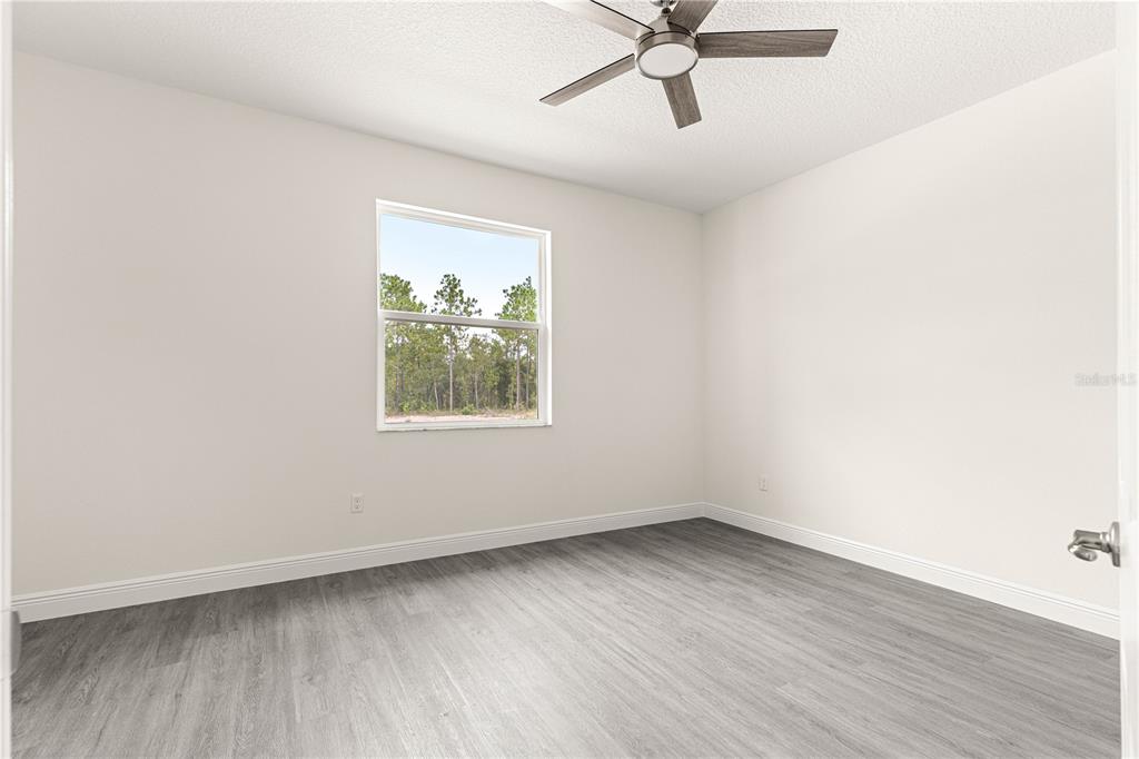 An entryway with gray wood-look flooring, a glass-paneled door, and a black geometric light fixture — 12185 SW 98TH STREET, DUNNELLON, FL