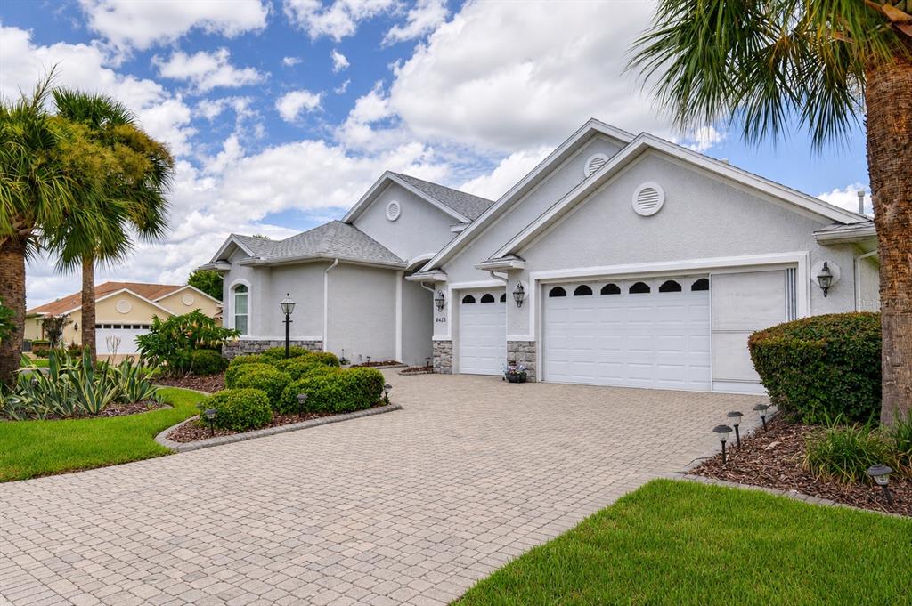 A light-colored house with a paver driveway, a two-car garage, and palm trees — 8616 SW 82ND TERRACE, OCALA, FL