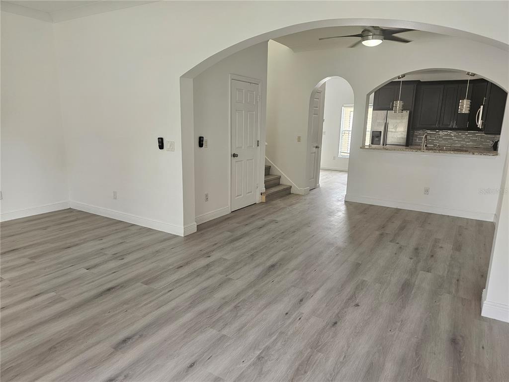 An open-concept living area features light wood-look flooring, arched doorways, and a kitchen with dark cabinets — 9153 OAK FERN DRIVE, ORLANDO, FL