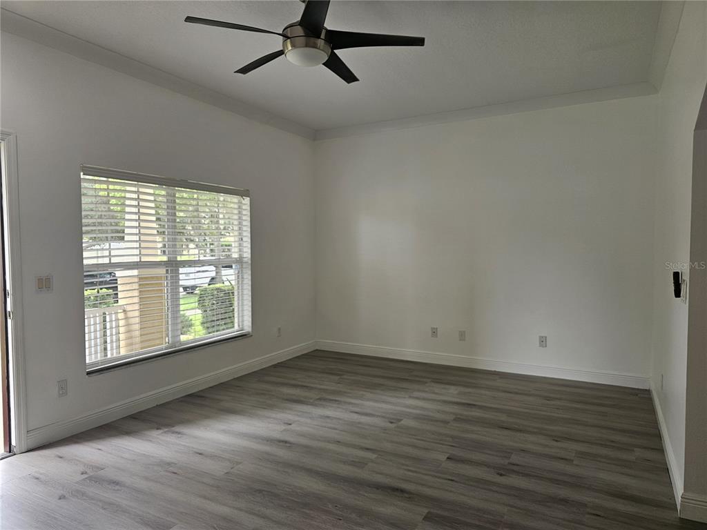 An empty room with white walls, gray wood-look flooring, a ceiling fan, and a window — 9153 OAK FERN DRIVE, ORLANDO, FL