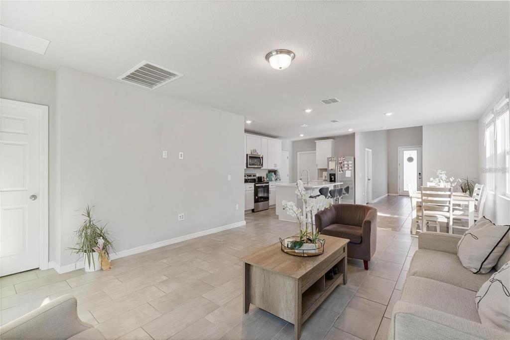An open-concept living room and kitchen with light tile flooring and neutral walls — 17411 MILLION LAKES COURT, CLERMONT, FL