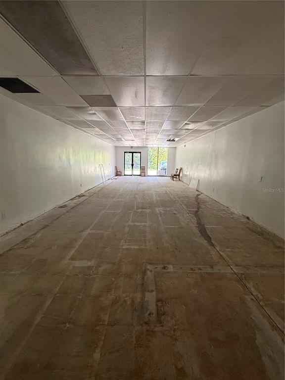 An empty commercial space features a drop ceiling, white walls, and a bare concrete floor — 3380 SE LAKE WEIR AVENUE UNIT F, OCALA, FL