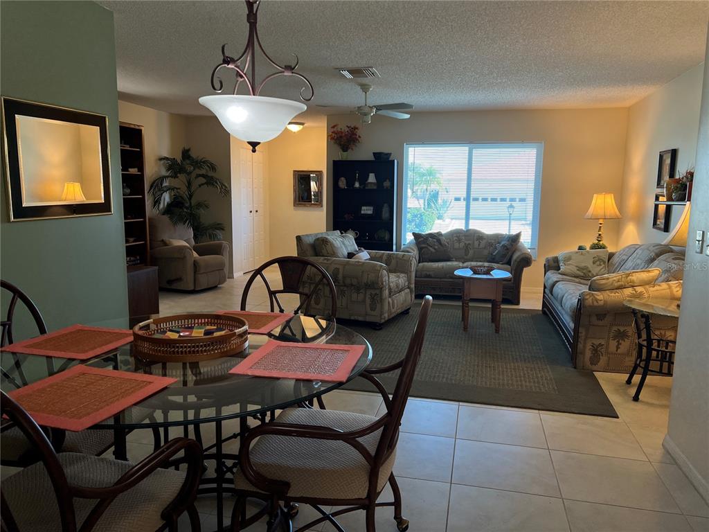 A dining area with a glass table overlooks a living room featuring patterned furniture — 1814 COLUMBINE PLACE, SUN CITY CENTER, FL