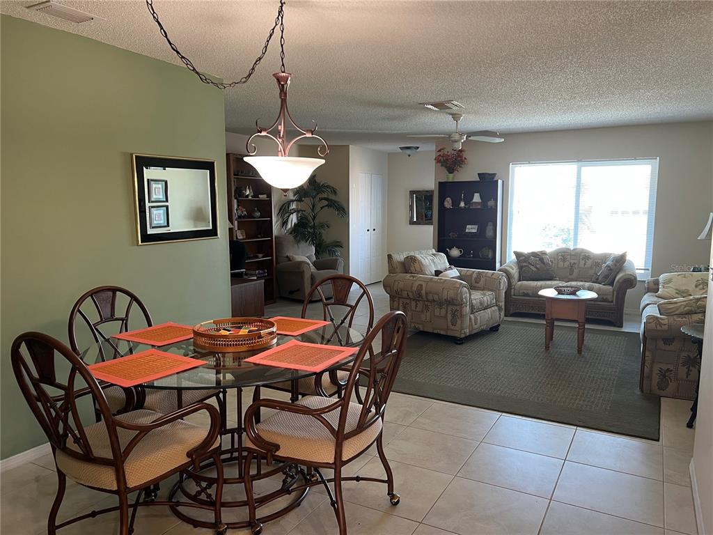 A dining area with a glass table and chairs opens into a living room — 1814 COLUMBINE PLACE, SUN CITY CENTER, FL