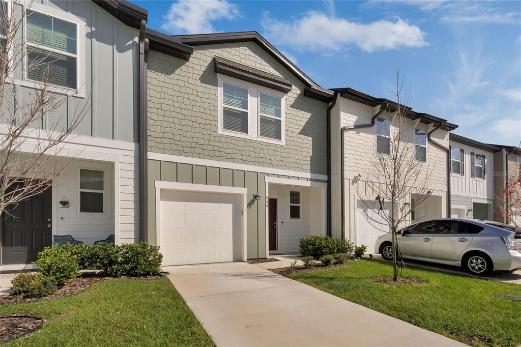 A two-story townhouse exterior with a single-car garage, light green siding, and a concrete driveway — 840 GRANDIN STREET, DAVENPORT, FL
