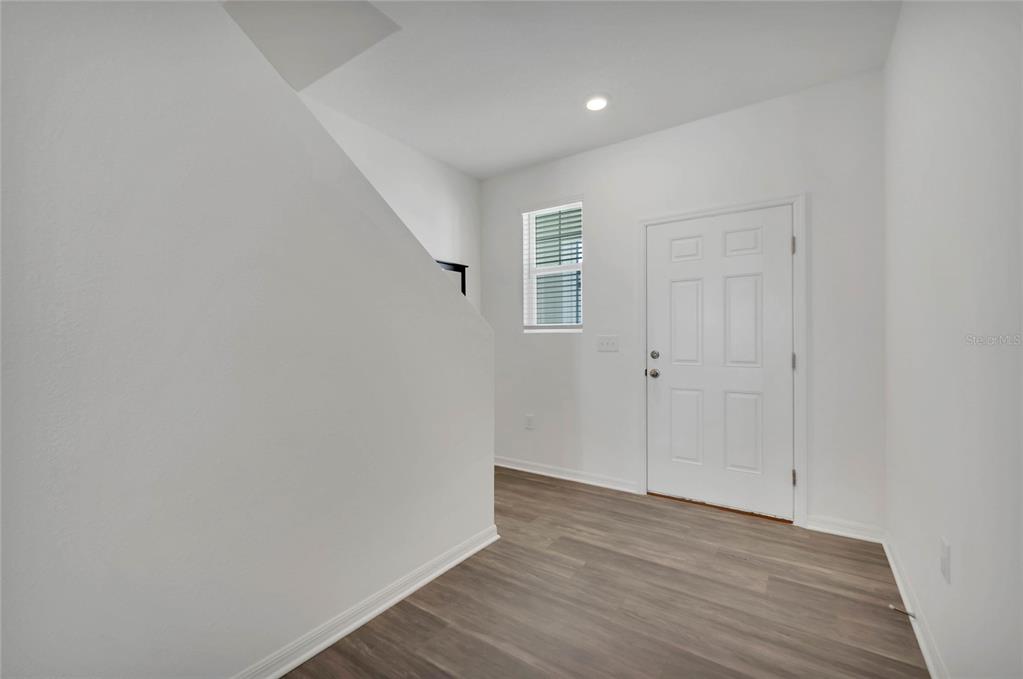 An entryway features white walls, wood-look flooring, a window with blinds, and a white door — 840 GRANDIN STREET, DAVENPORT, FL