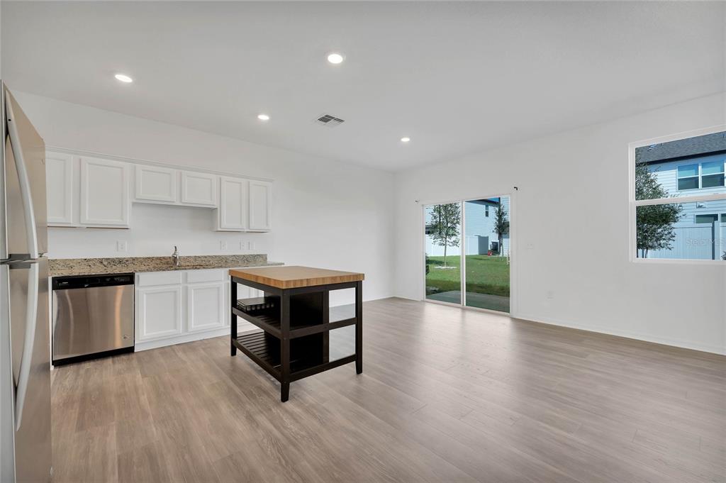 A kitchen with white cabinets, granite countertops, stainless steel appliances, and a portable wooden island — 840 GRANDIN STREET, DAVENPORT, FL