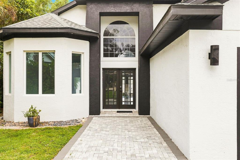 A paved walkway leads to the double front doors of a white house with black trim — 673 LAKE HARBOR CIRCLE, ORLANDO, FL