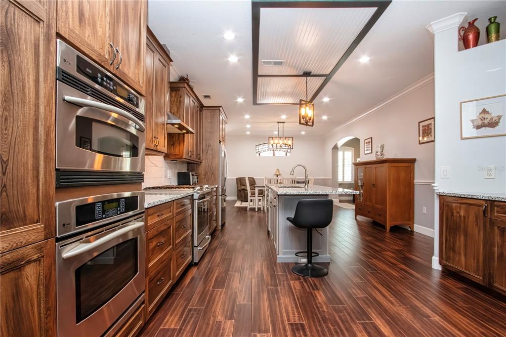 A kitchen features wood cabinets, stainless steel appliances, a center island, and dark wood flooring — 515 PLANTERS MANOR WAY, BRADENTON, FL