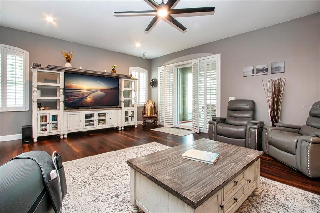 A living room features dark wood floors, a large entertainment center, and gray leather recliners — 515 PLANTERS MANOR WAY, BRADENTON, FL