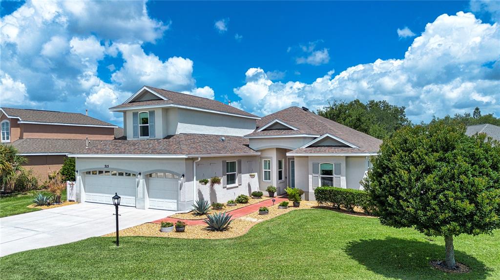 A two-story suburban house features a two-car garage, a red walkway, and a manicured lawn — 515 PLANTERS MANOR WAY, BRADENTON, FL