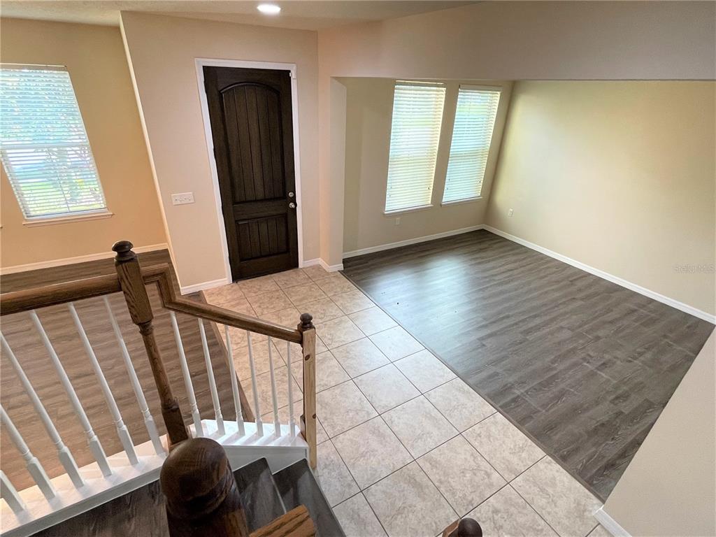 An entryway with tiled flooring leads to a living area with wood-look flooring and stairs — 8415 MOREHOUSE DRIVE, ORLANDO, FL