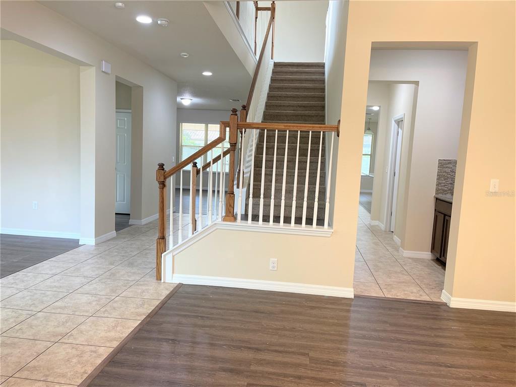An interior view shows a staircase with wooden railings and carpeted steps in a foyer — 8415 MOREHOUSE DRIVE, ORLANDO, FL
