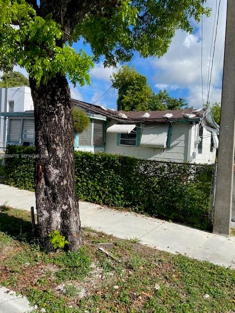 A single-story house with a damaged roof is partially obscured by a large tree — 1239 NW 60th St, Miami FL 33142, MIAMI, FL
