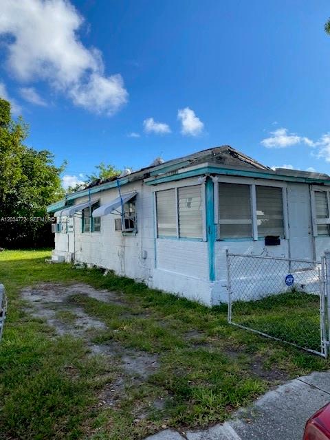 A white, single-story house with a metal roof and a chain-link fence — 1239 NW 60th St, Miami FL 33142, MIAMI, FL