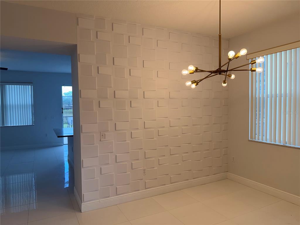 A dining area features a white 3D textured accent wall and a modern sputnik chandelier — 1112 PINE RIDGE DRIVE, DAVENPORT, FL