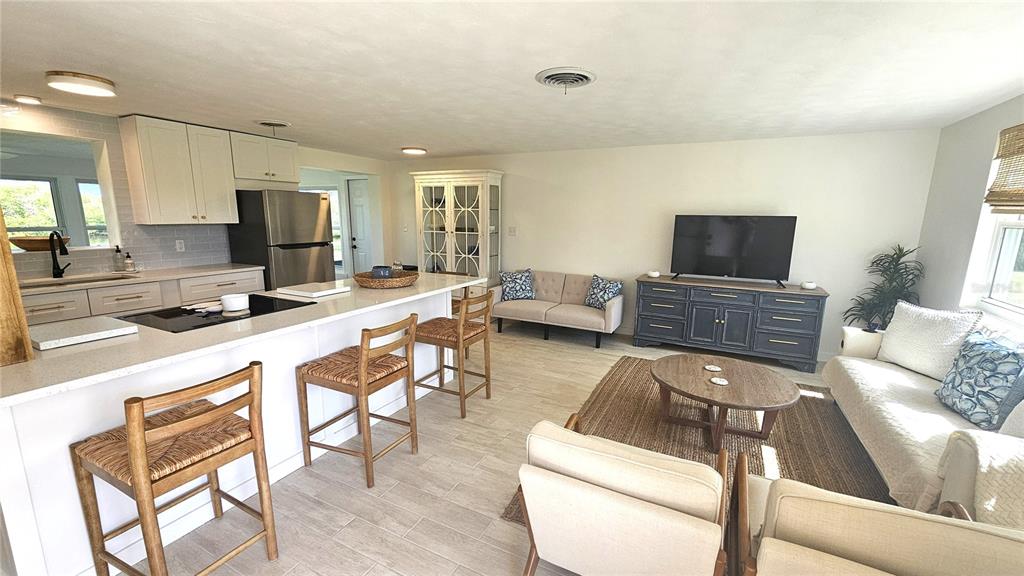 An open-concept kitchen and living area features a white island, light tile flooring, and furniture — 1210 S MARYKNOLL ROAD, ENGLEWOOD, FL