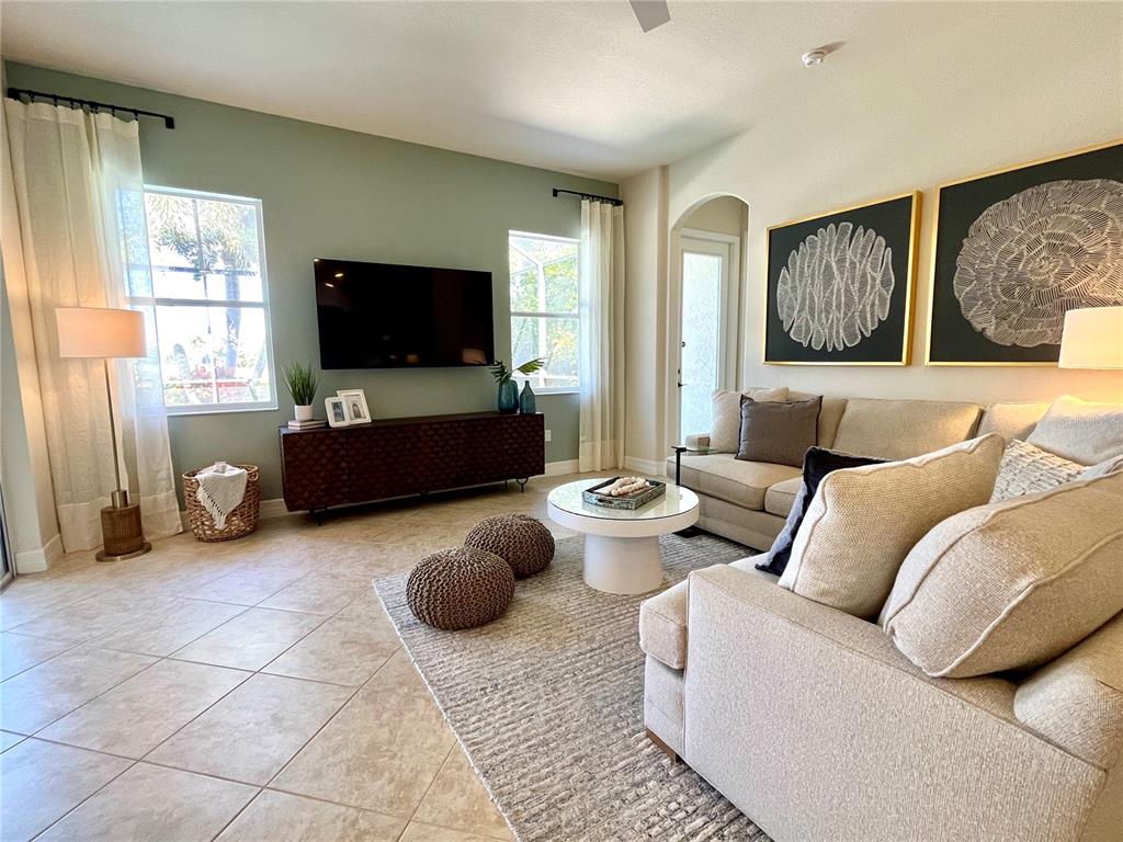 A living room features a green accent wall, a television, and a beige sectional sofa — 7709 RIVER PRESERVE DRIVE, BRADENTON, FL