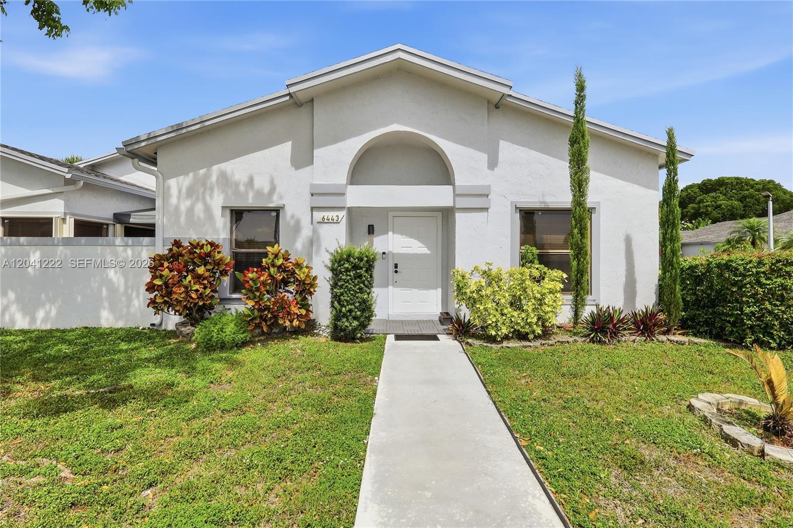 A single-story white house features a front walkway, arched entryway, and landscaped front yard — 6443 SW 152nd Cir Pl # 43, Miami FL 33193, MIAMI, FL