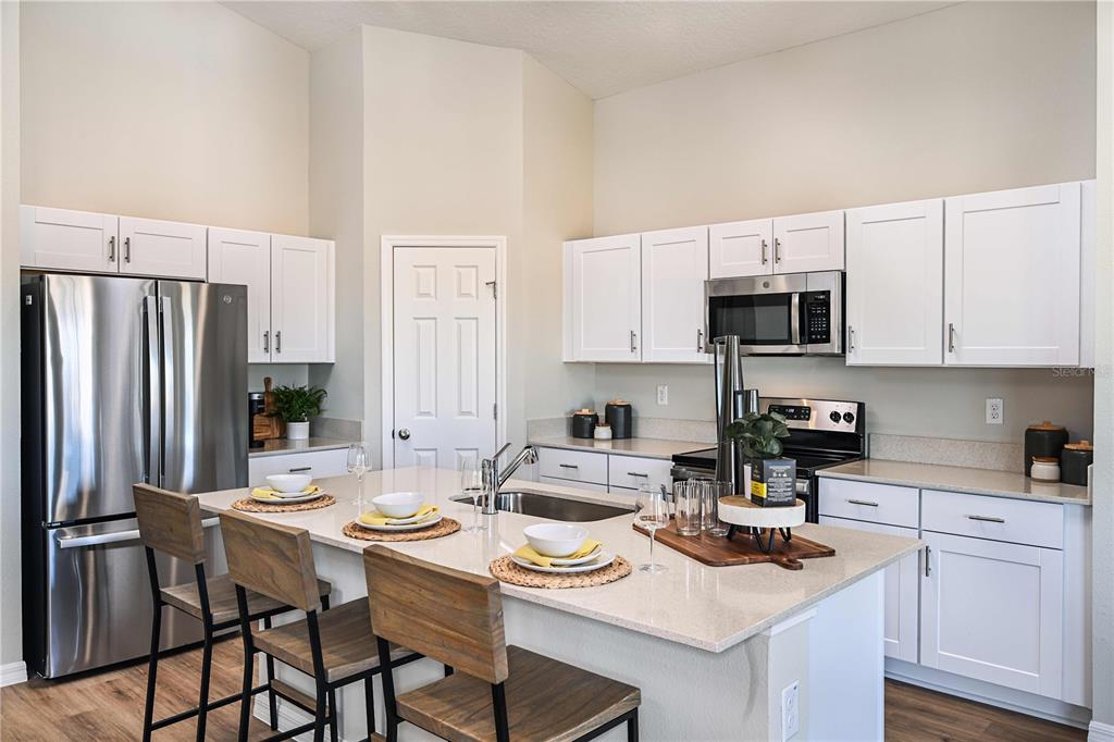 A kitchen features white cabinets, stainless steel appliances, and a central island with bar seating — 1815 POPPY DRIVE, LAKE HAMILTON, FL