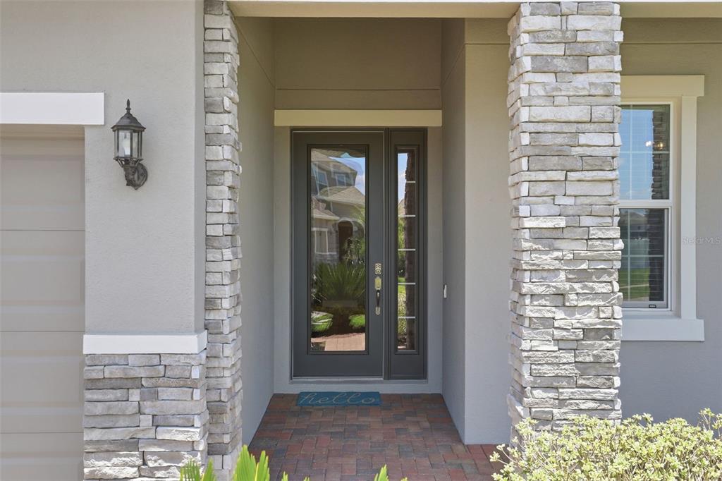 A front entryway features a dark door with a sidelight, stone pillars, and brick pavers — 832 JETWAY STREET, ORANGE CITY, FL