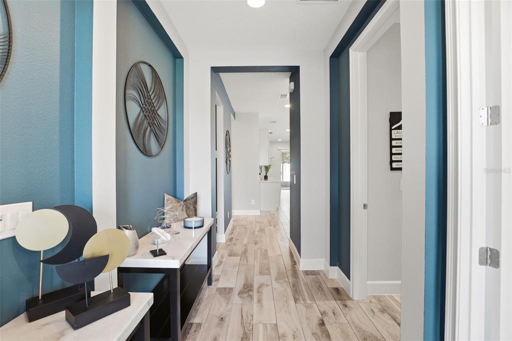 A hallway with blue accent walls, wood-look tile flooring, and a modern console table — 832 JETWAY STREET, ORANGE CITY, FL