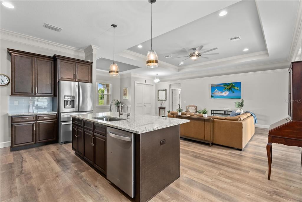 A kitchen with dark wood cabinets and a granite island opens into a living room — 1538 KEYHOLE STREET, NORTH PORT, FL