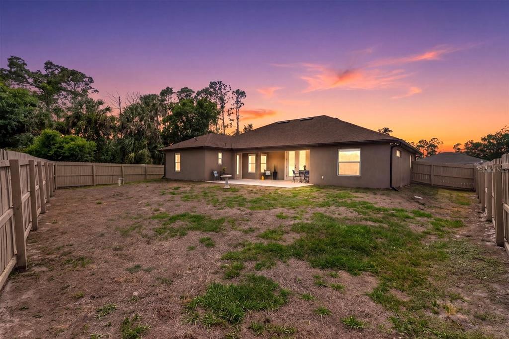 The backyard of a single-story house features a concrete patio and a wooden privacy fence — 1538 KEYHOLE STREET, NORTH PORT, FL