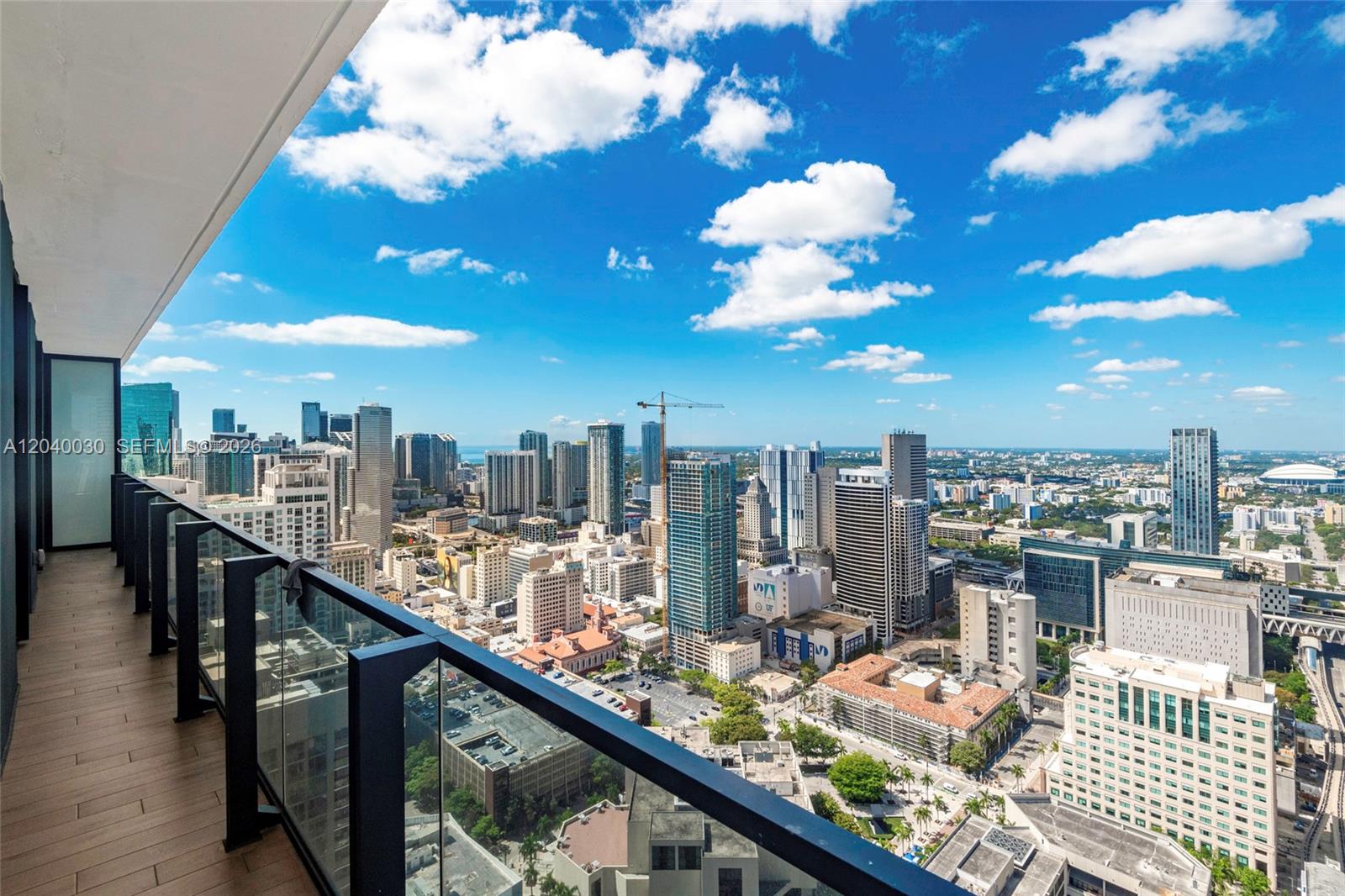 A high-rise balcony with a glass railing overlooks a dense urban cityscape under a blue sky — 398 NE 5th St # 4001, Miami FL 33132, MIAMI, FL