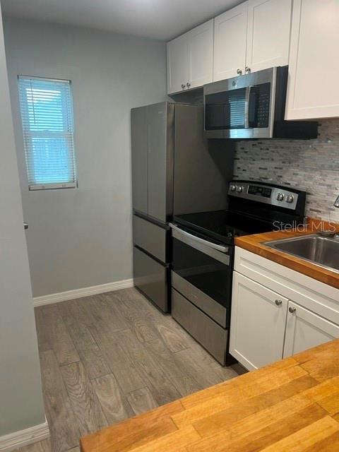 An empty bedroom features light blue walls, wood-look flooring, a ceiling fan, and a window — 2808 W AZEELE UNIT 103, TAMPA, FL