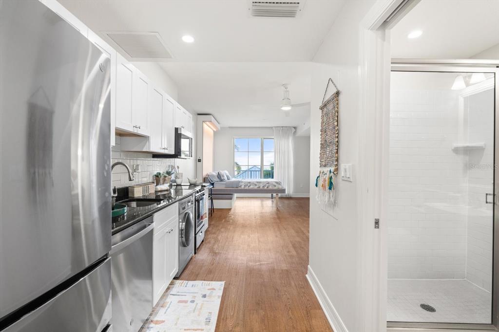 A studio apartment features a kitchen with stainless appliances, wood flooring, and a walk-in shower — 536 BAHIA BEACH BOULEVARD UNIT 311A, RUSKIN, FL