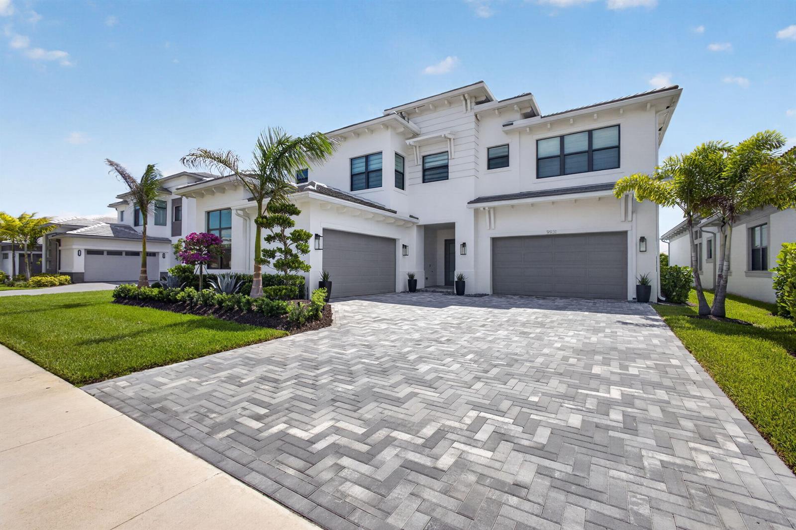 A two-story white house with a grey paver driveway and three garage doors — 9931 Migration Point, Palm Beach Gardens FL 33412, PALM BEACH GARDENS, FL