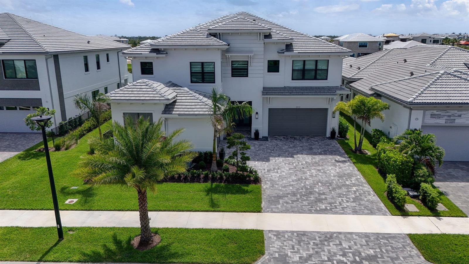 An aerial view of a two-story white house with a gray tiled roof and driveway — 9931 Migration Point, Palm Beach Gardens FL 33412, PALM BEACH GARDENS, FL